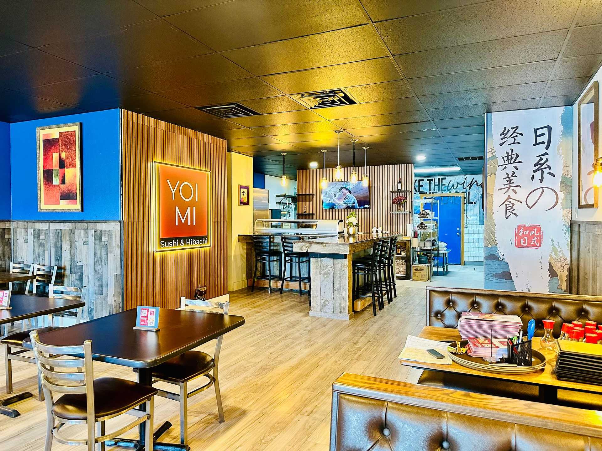Bright, modern sushi restaurant with wood accents, colorful art, and a neon "YOI MI" sign.